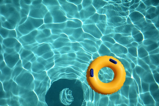 Yellow pool ring floating in a refreshing cool blue swimming pool.