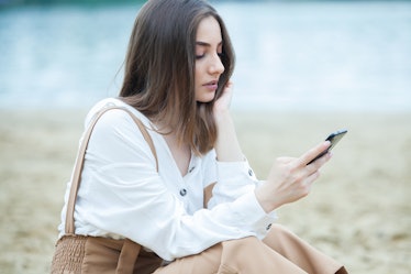 Girl outdoors texting on her mobile phone. Girl with phone. Portrait of a happy woman text sms messa...