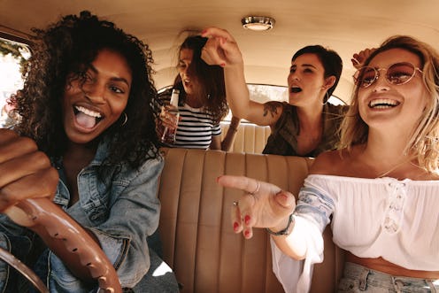 Young african woman driving the car with her friends having fun in the car. Crazy young female frien...