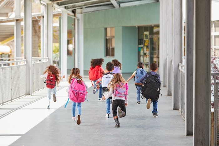 Elementary school kids run from camera in school corridor