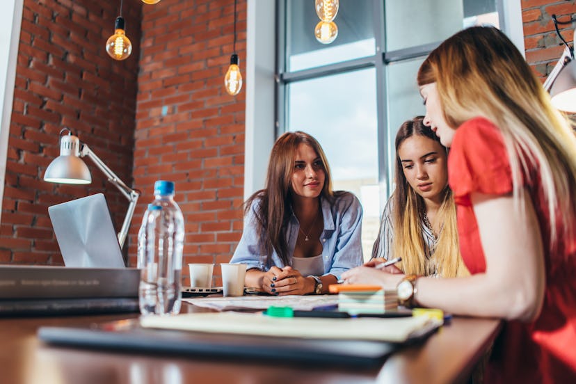 Group of female coworkers working on new project sitting at desk in creative office