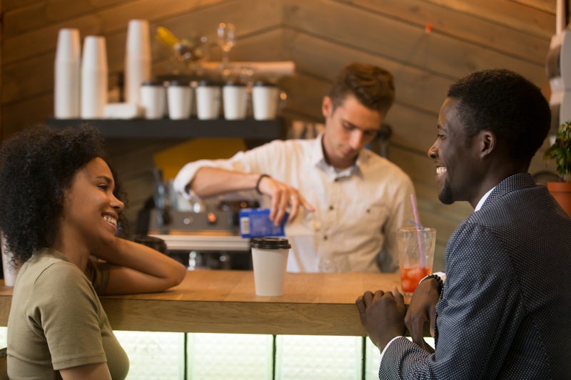 African american man and woman flirting talking at bar counter, black couple enjoying drinks and ple...