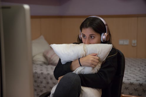 scared girl watching at a horror movie in her room