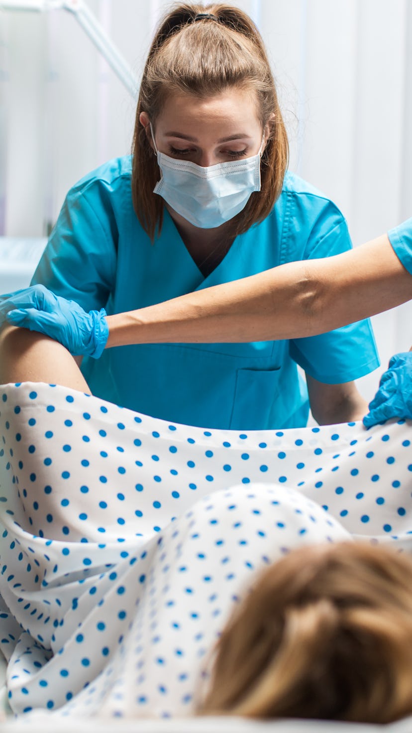 In the Hospital Woman Giving Birth, Husband Holds Her Hand in Support, Obstetricians Assisting. Mode...