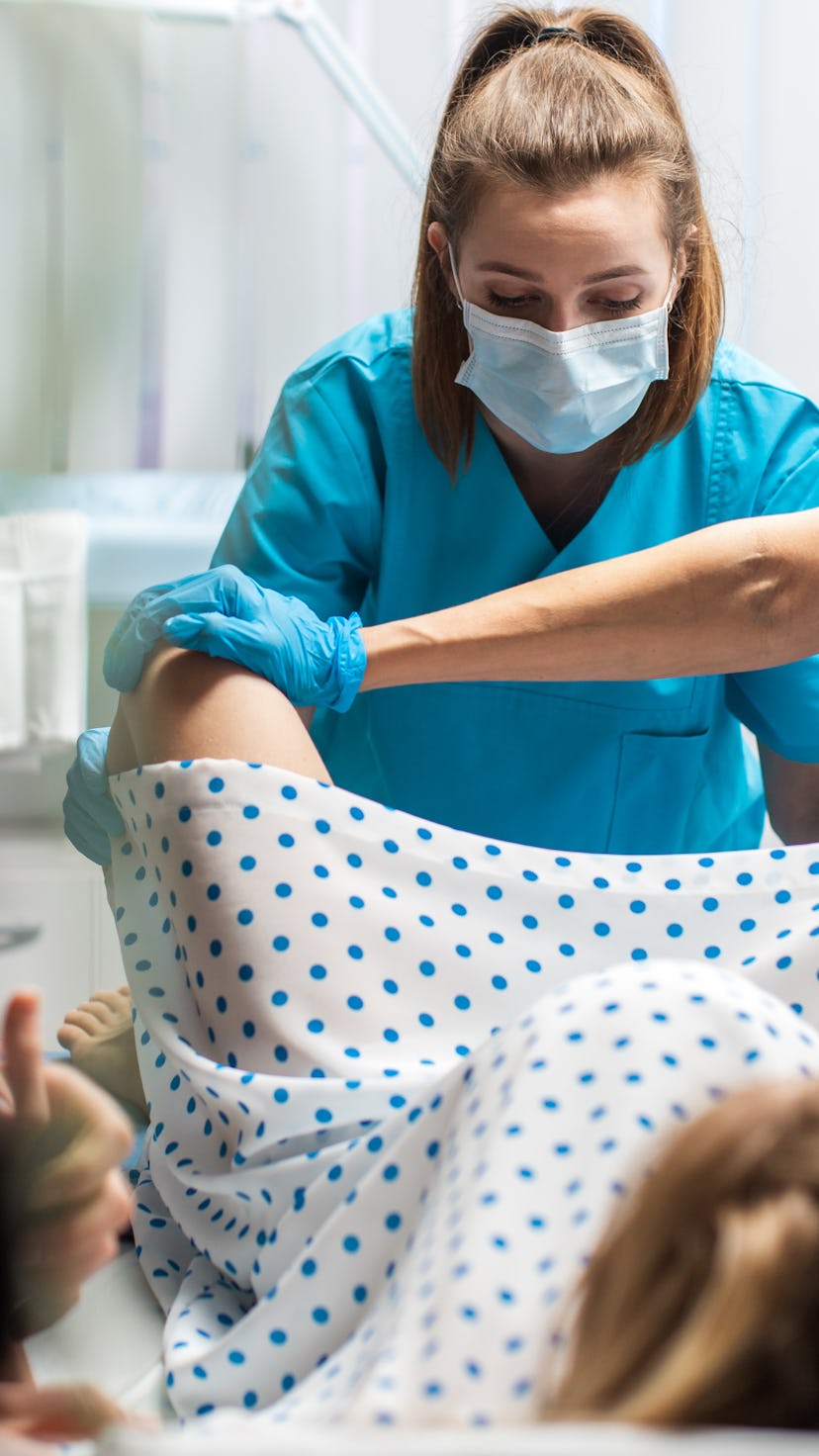 In the Hospital Woman Giving Birth, Husband Holds Her Hand in Support, Obstetricians Assisting. Mode...