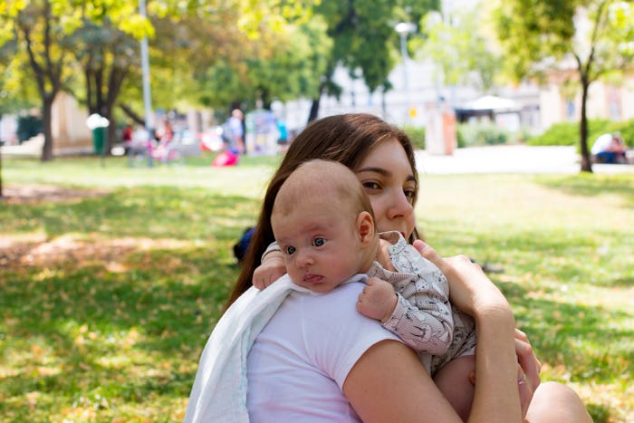 Portrait of the mother and child, little baby resting head on the mom's shoulder, burping position a...