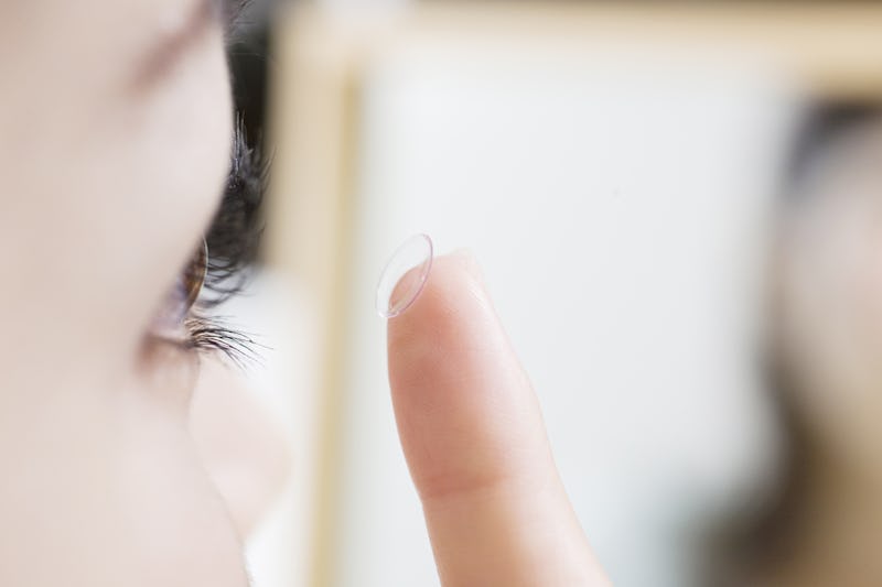 Japanese women trying to put contact lenses on an eye