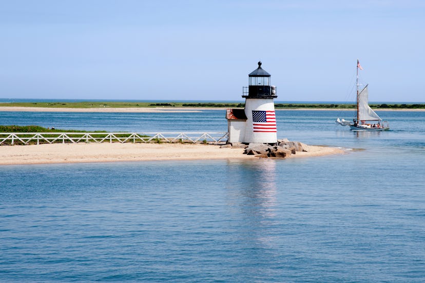Sailing past Brant Point lighthouse on Nantucket Island on a warm quiet summer day in New England. A...