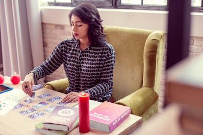 My workplace. Nice brunette woman sitting at the table while looking at the tarot cards