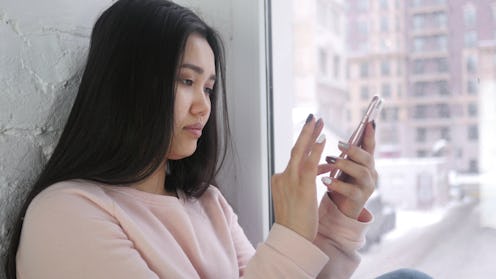 Young Asian Woman Browsing Smartphone, Sitting at Window