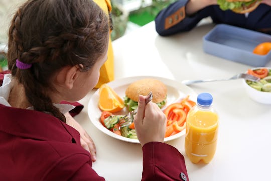 Children sitting at cafeteria table while eating lunch