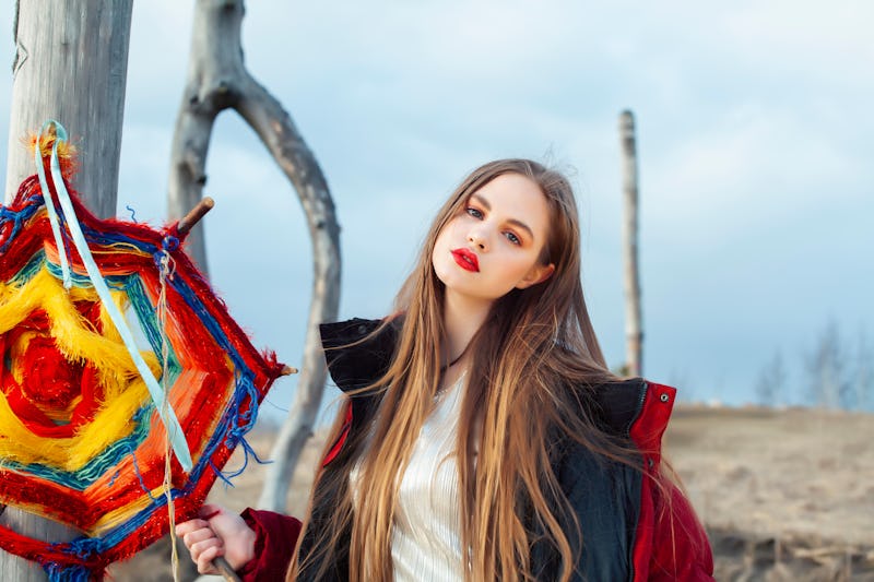 fashion style dressed girl with dreamcatcher outside in field, making witchcraft ritual at halloween