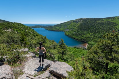 Female hiker reaching the top of an overlook of Jordan Pond at Acadia National Park 