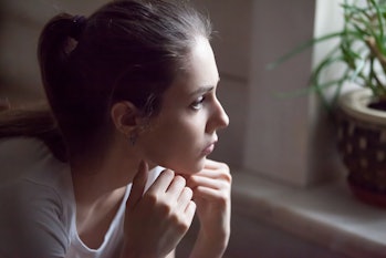 Upset young woman look far in window thinking about personal troubles, sad female feeling blue after...