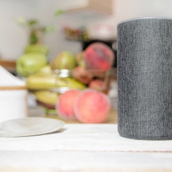 Personal assistant connected loudspeaker on a wooden table in a Smart Home in a kitchen. Next, some ...