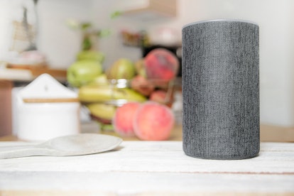 Personal assistant connected loudspeaker on a wooden table in a Smart Home in a kitchen. Next, some ...