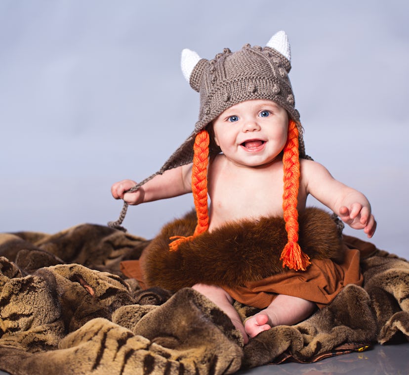 Little boy sitting on the fur in viking style hat