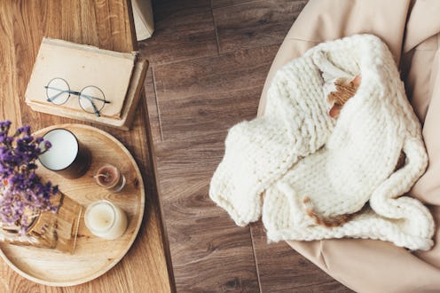 Ginger kitten sleeping on knitted woolen sweater. Wooden tray with home decor near the window. Fall ...