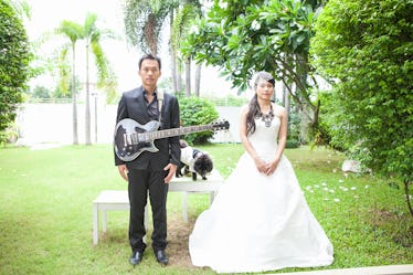 Bride and groom is happy play guitar in the lawn with dog