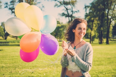 Girl with rainbow-colored air balloons in a park.