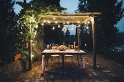 Decorated outdoor wedding table with flowers, lights and candles in rustic style