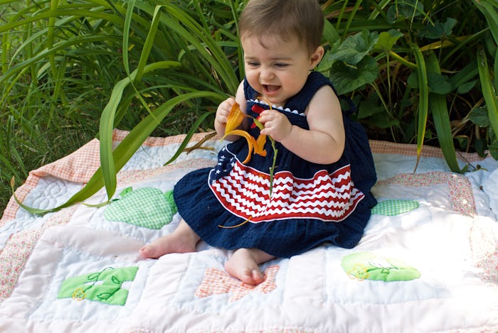 Caucasian baby girl wearing patriotic dress outside in tiger lillies