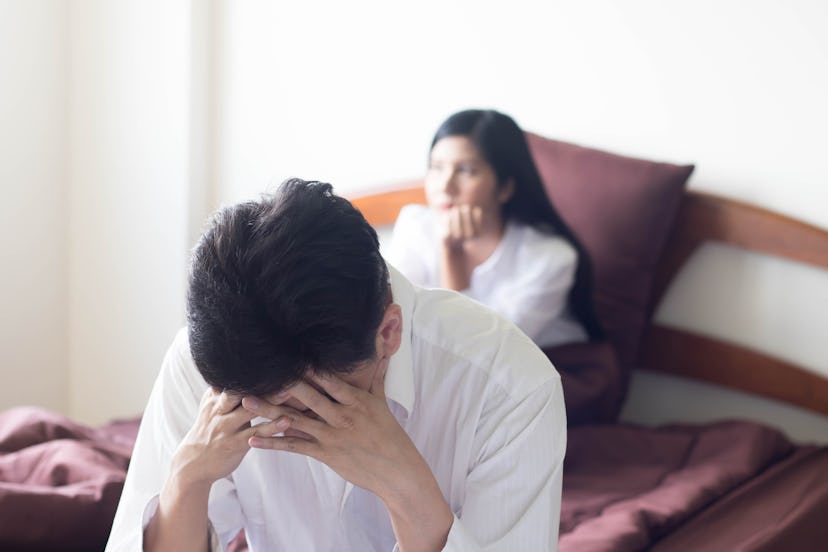 Asian man, who wear white shirt on red bed with angry wife,  feeling disappointed and depressed beca...