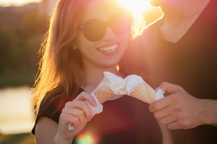 happy californian couple in love in summer park. beautiful woman and handsome man eat ice cream in a...