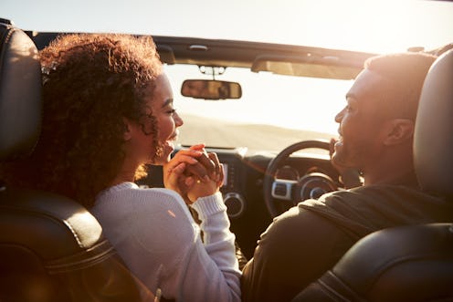 Couple driving look at each other, hold hands, passenger POV