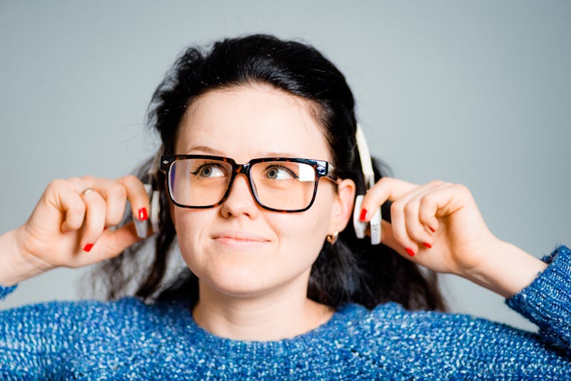 business woman listening to wireless headphones isolated on gray background