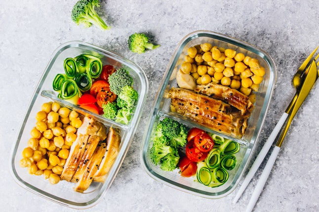 Healthy meal prep containers with chickpeas, chicken, tomatoes, cucumbers, avocados and broccoli. Top view