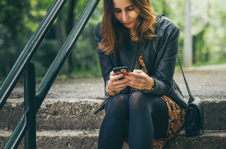 Woman looking at cell phone with worried expression on face.