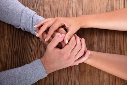 Loving Couple Holding Hands On Wooden Desk