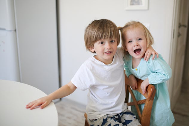 brother and sister siblings tenderly embrace on a light background in a real interior, the concept o...