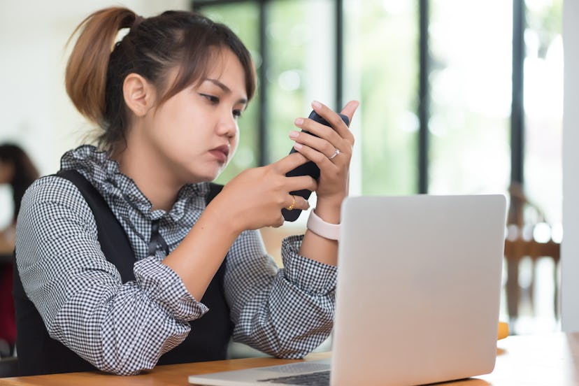 Asian woman working with her laptop and smart phone.