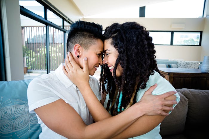 Lesbian couple embracing each other on sofa in living room