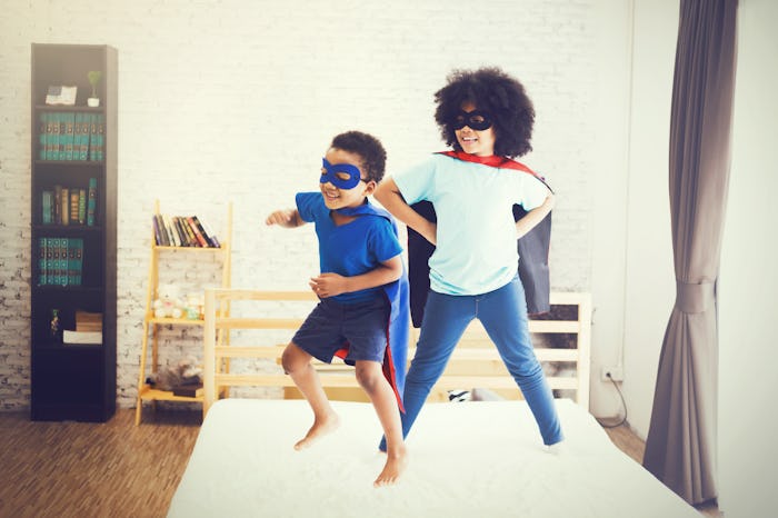 African American happy and confident young kids playing
and dressing up as superhero together in b...