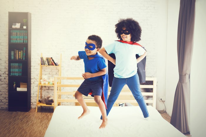 African American happy and confident young kids playing 
 and dressing up as superhero together in b...