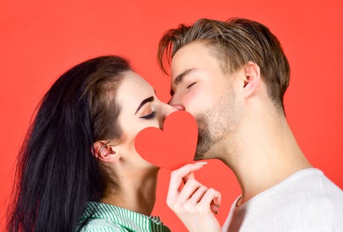 Love and foreplay. Romantic kiss concept. Couple in love kissing and hide lips behind heart card. Ce...
