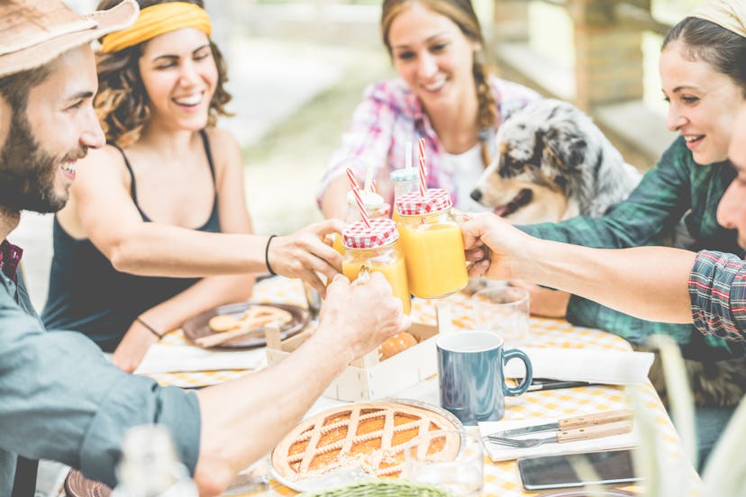 Happy millennial friends cheering at breakfast brunch meal in nature outdoor - Young people having f...