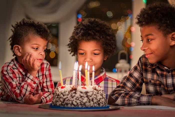 Black children with birthday cake. Three boys at birthday table. Happy birthday, brother. Watching t...