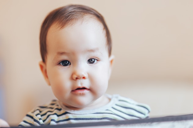 pretty baby infant boy or girl sitting inside a box in apartment.