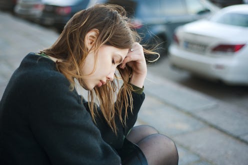 Young sad woman sitting on the stairs in the street
