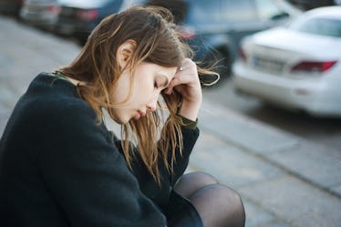 Young sad woman sitting on the stairs in the street