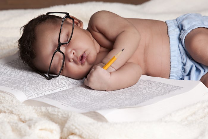Adorable newborn sound asleep on a big book.