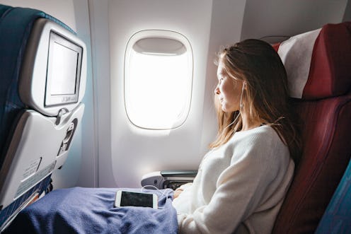 Teenage girl looking at plane window during flight. Young passenger travelling by airplane by first ...