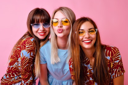 Lovable group of stylish girls smiling and sending kiss on camera, super trendy tropical print cloth...