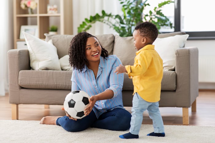 childhood, kids and people concept - happy african american mother and her baby son playing with soc...
