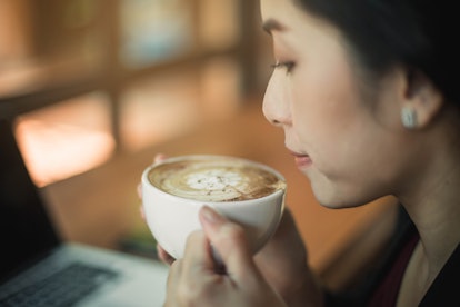 Woman drinking coffee in a cafe. Portrait of happy brunette with mug in hands.