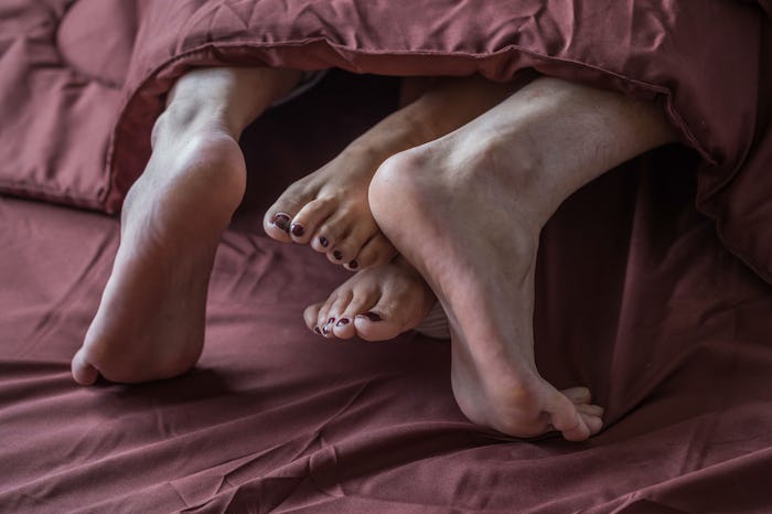 Legs of men and women are having sex on a brown bed.